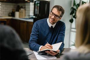 Happy wealth advisor in Chattanooga communicating with a couple and taking notes into his notebook.