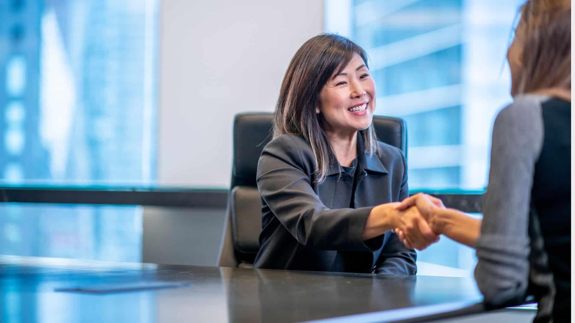 Two women shaking hands after setting up a payable on death account with a financial advisor.